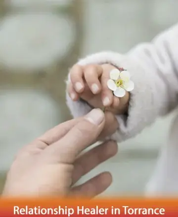 In a serene exchange, a gentle hand offers a delicate blossom to a tiny, trusting grip, symbolizing the tender connection and nurturing support we all seek. This moment captures the essence of loving guidance in our lives. Relationship healer in Torrance.