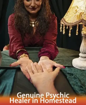 In a softly lit room, a gentle presence offers comfort and insight through a tender palm reading. The warm glow of a lamp casts a serene ambiance, inviting trust and a deep sense of peace. Genuine psychic healer in Homestead.