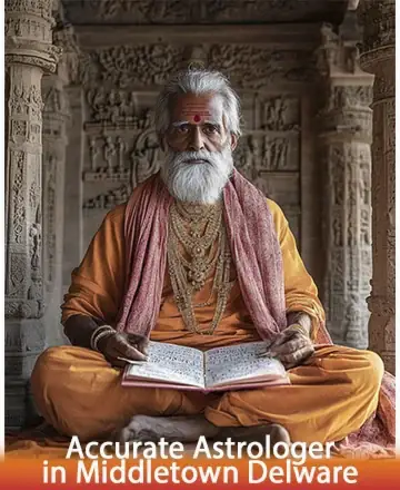 Elderly astrologer in traditional orange attire sitting cross-legged indoors with intricate stone carvings. He is holding an open book and looking directly at the camera. Text overlay reads, 