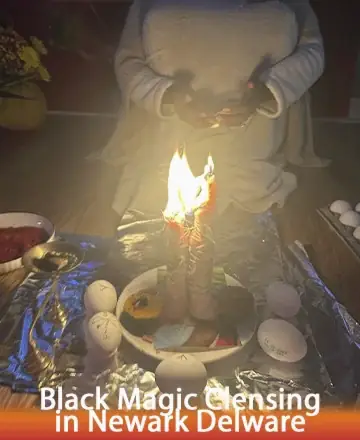 Person in white sits cross-legged performing a ritual with a lit candle surrounded by white eggs in a circle. Bowls and ritual items are arranged around the setup in dim lighting. Text reads 'Black Magic Cleansing in Newark Delaware