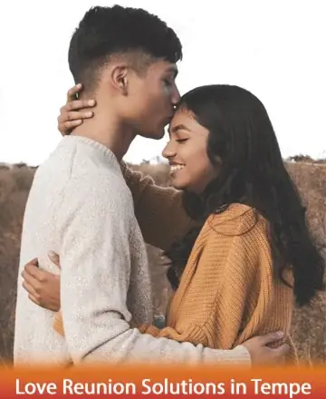 A young couple embracing in a field, with the man gently kissing the woman's forehead. Both are smiling and wearing cozy sweaters, creating an intimate and warm atmosphere. The setting appears to be outdoors with dry grass in the background. The bottom of the image contains text that reads, 