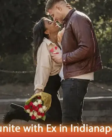 A couple stands closely, smiling at each other in a park. The woman holds a bouquet of red and white flowers, wearing a cream sweater. The man wears a brown leather jacket. Mood is romantic.